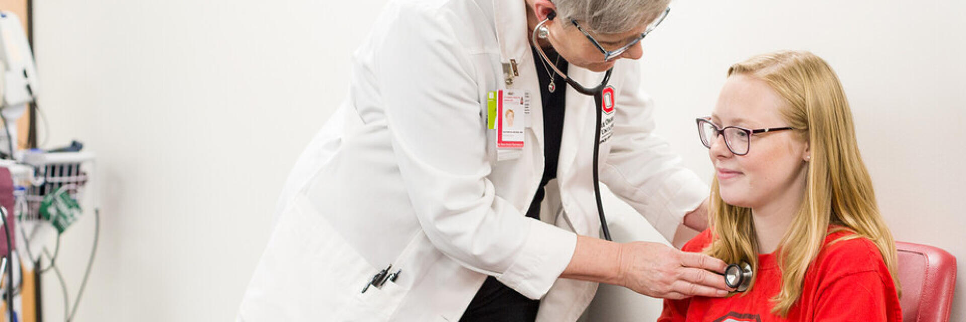 A healthcare professional examines an Ohio State student in a clinical exam room.